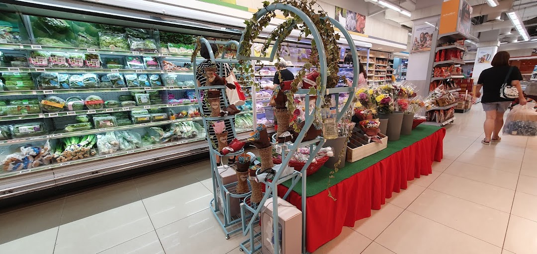 Supermarket interior with produce aisle, flower display, and shoppers.