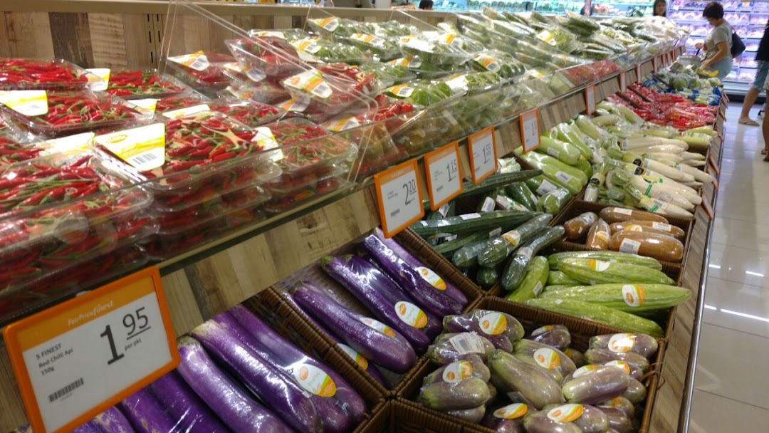 Rows of fresh vegetables and produce displayed in a supermarket aisle.