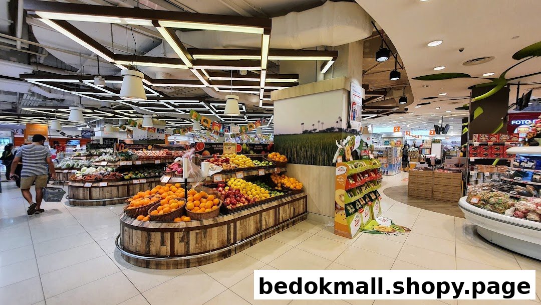 Interior view of a supermarket with fresh produce displays and a customer.