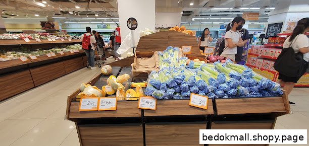 Interior view of a supermarket with fresh produce displays and customers.