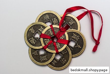 Several antique-style Chinese coins tied together with a red ribbon.