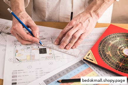 Hands drawing on architectural plans with a Fengshui compass.