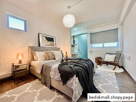 Modern bedroom with bed, nightstand, chair, and glass-enclosed bathroom.