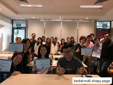 Group of people holding certificates in a classroom or training setting.