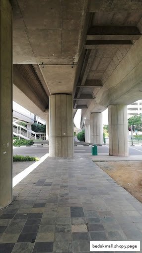 Pillars and elevated concrete structure over a paved walkway.