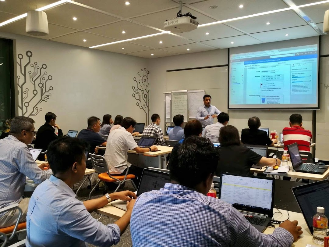 People attend a training session in a classroom with laptops and a projector.