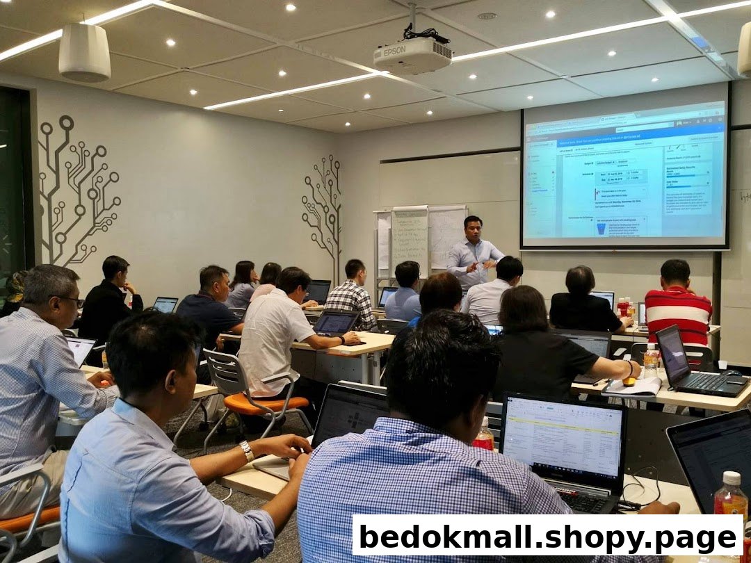 People attend a training session in a classroom with laptops and a projector.