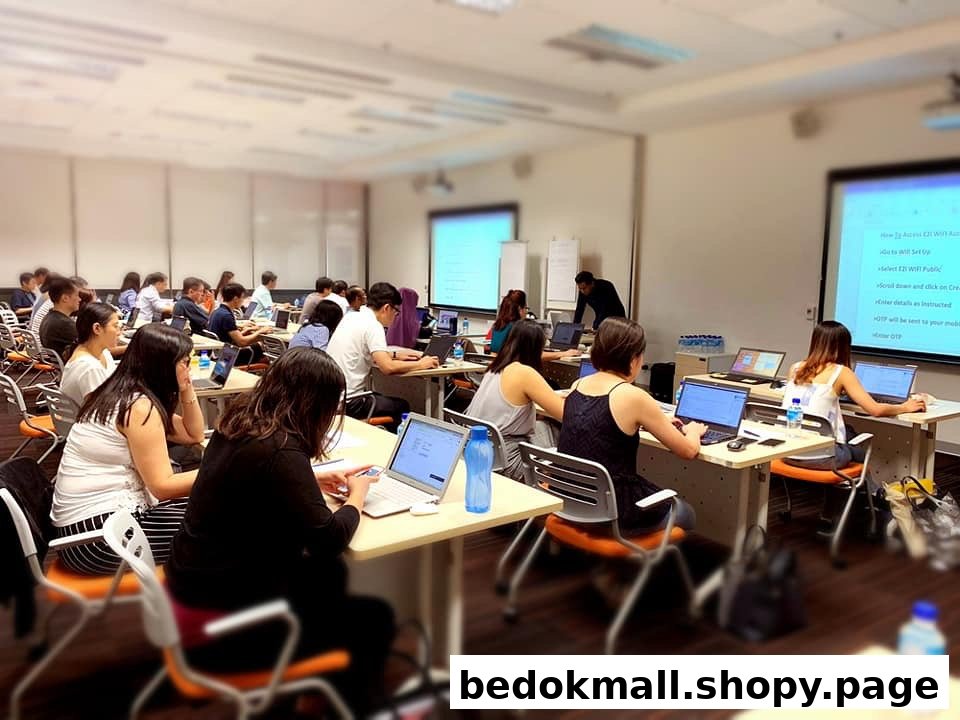 People in a classroom setting using laptops with projected screens.