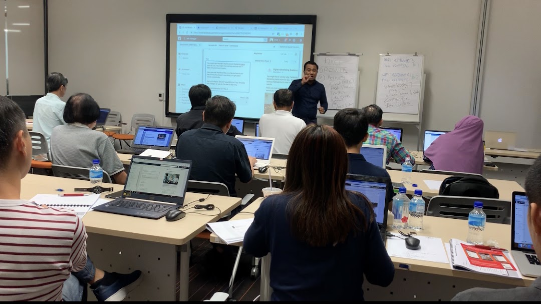 People attending a class or workshop with laptops and a presenter.