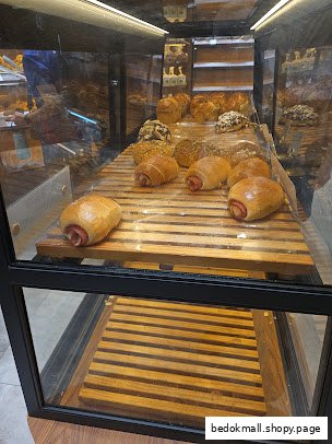 Glass display case with various breads and pastries in a bakery.
