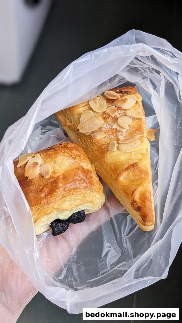 Two pastries in a plastic bag held by a hand.