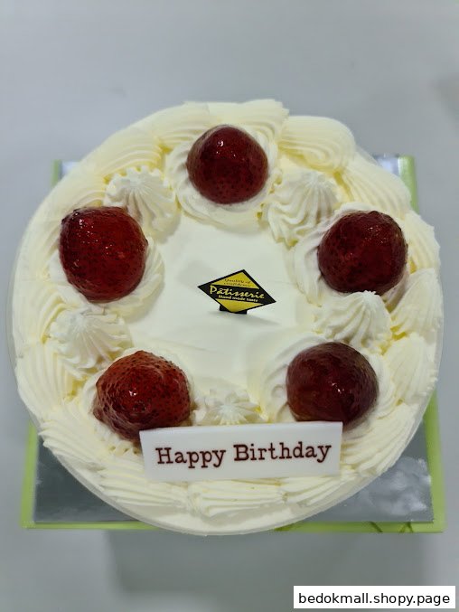 White frosted birthday cake with strawberries and a 'Happy Birthday' sign.