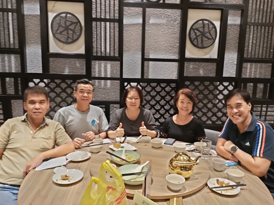 Five people are seated around a round table, dining in a restaurant.