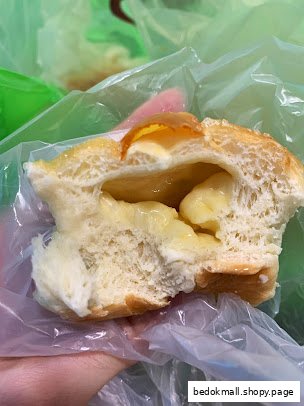 Close-up of a bun with creamy filling, held in a plastic bag.