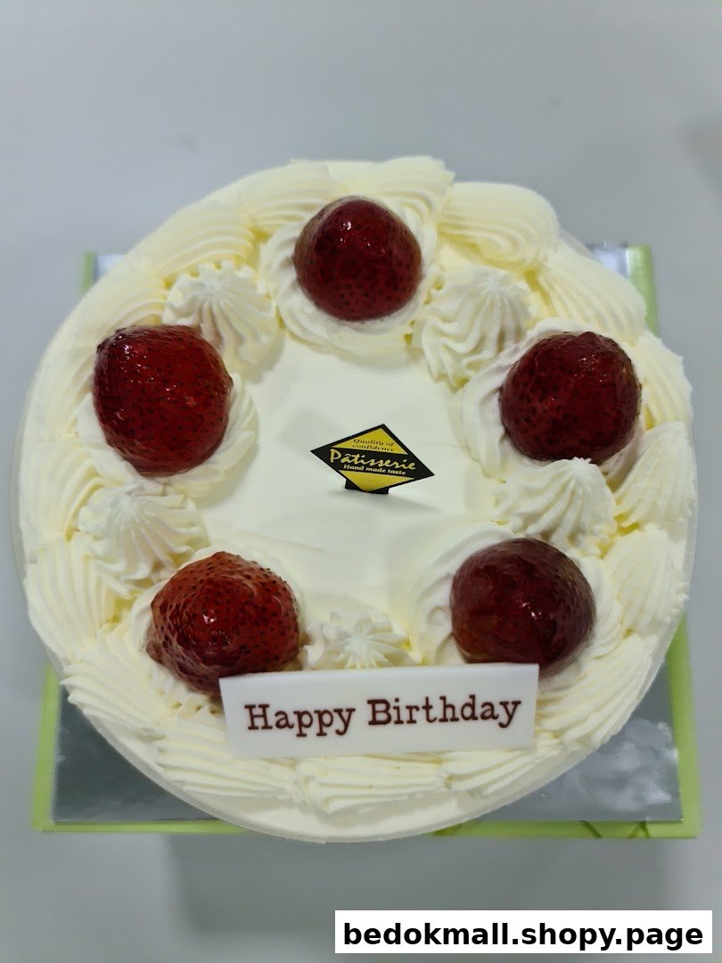 A white cake topped with strawberries, whipped cream, and a 'Happy Birthday' plaque.