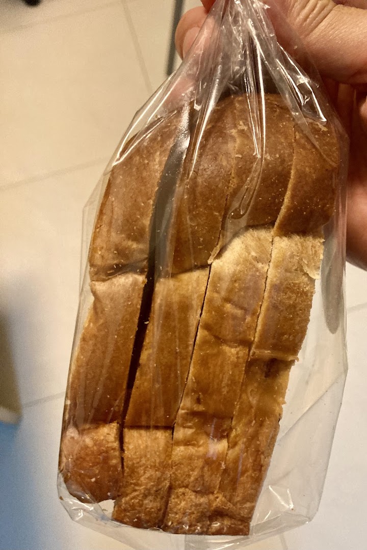 Hand holding a plastic bag containing a loaf of sliced bread.