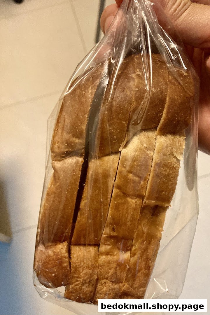 Hand holding a plastic bag containing a loaf of sliced bread.