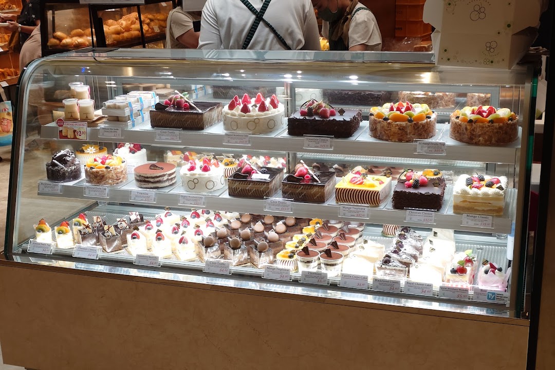 A display case filled with various cakes and pastries inside a bakery.