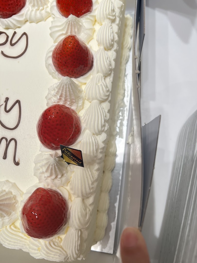 A white cake with strawberries and whipped cream, partially in a box.