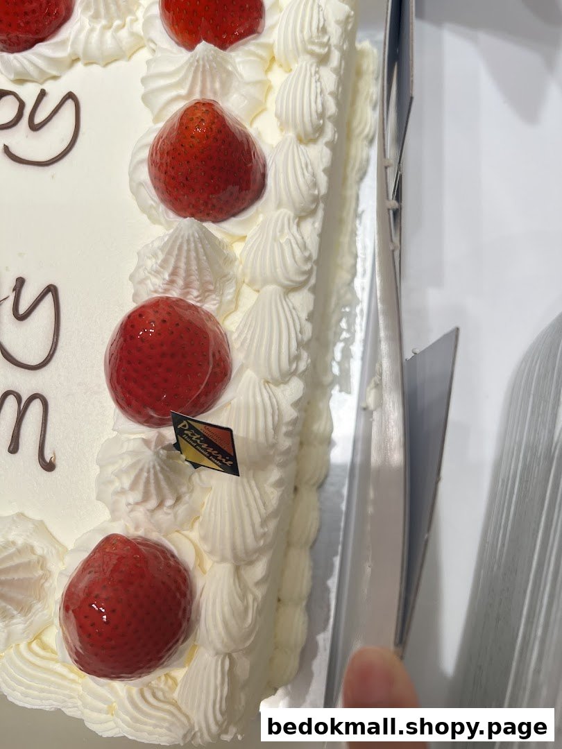 A white cake with strawberries and whipped cream, partially in a box.