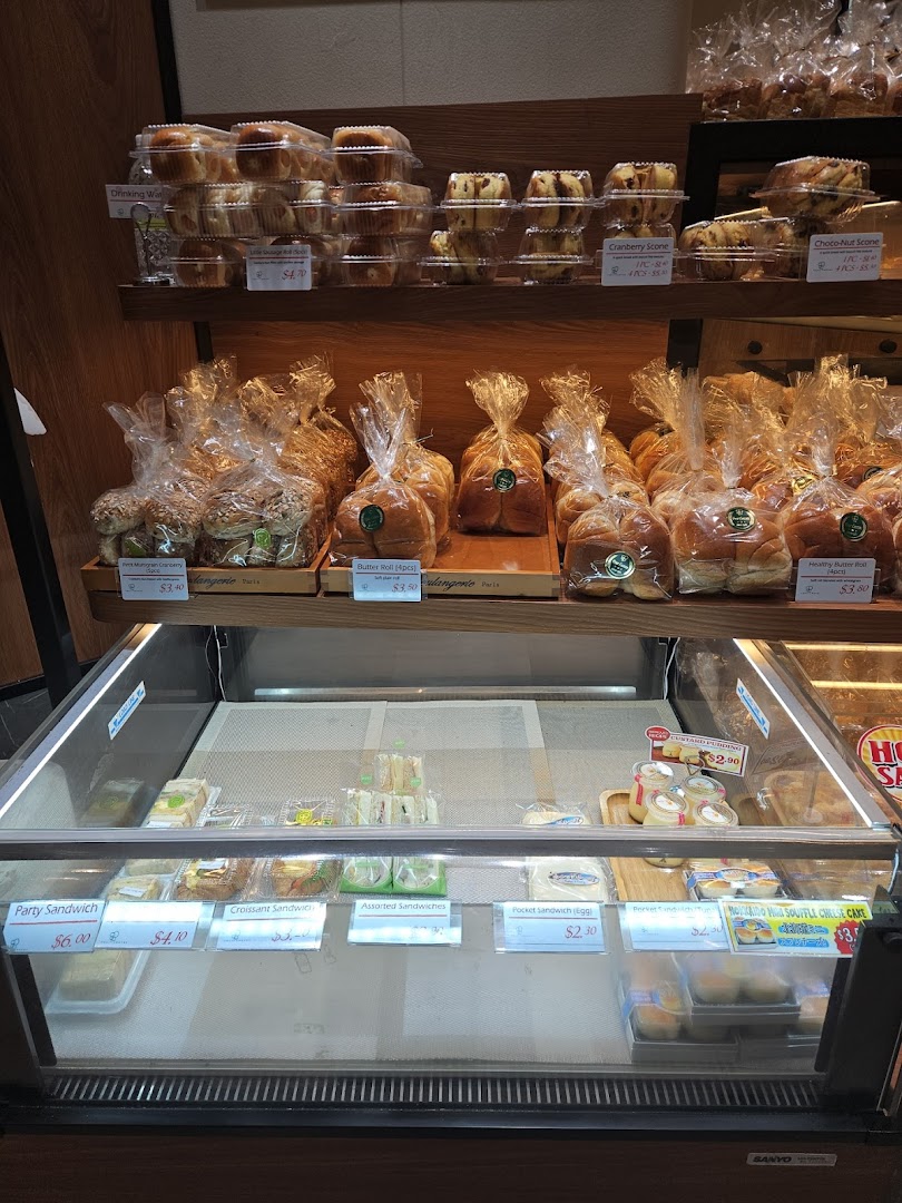 Interior view of a bakery display with various packaged bread, pastries, and sandwiches.