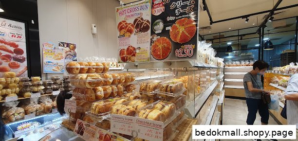 Interior of a bakery with shelves of bread and customers browsing.