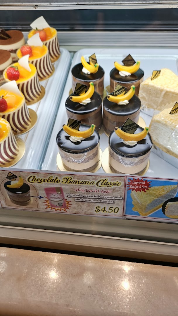 Cakes and pastries displayed in a glass case with a price tag.