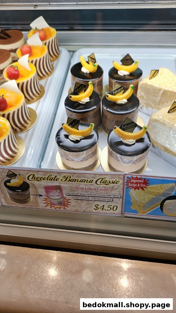 Cakes and pastries displayed in a glass case with a price tag.
