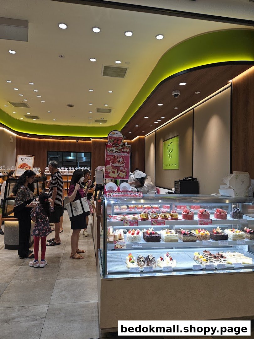 Bakery interior with customers, staff, and a display case full of cakes.