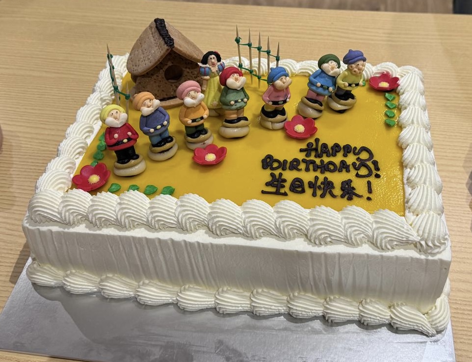 A birthday cake decorated with Snow White and Seven Dwarfs figures.