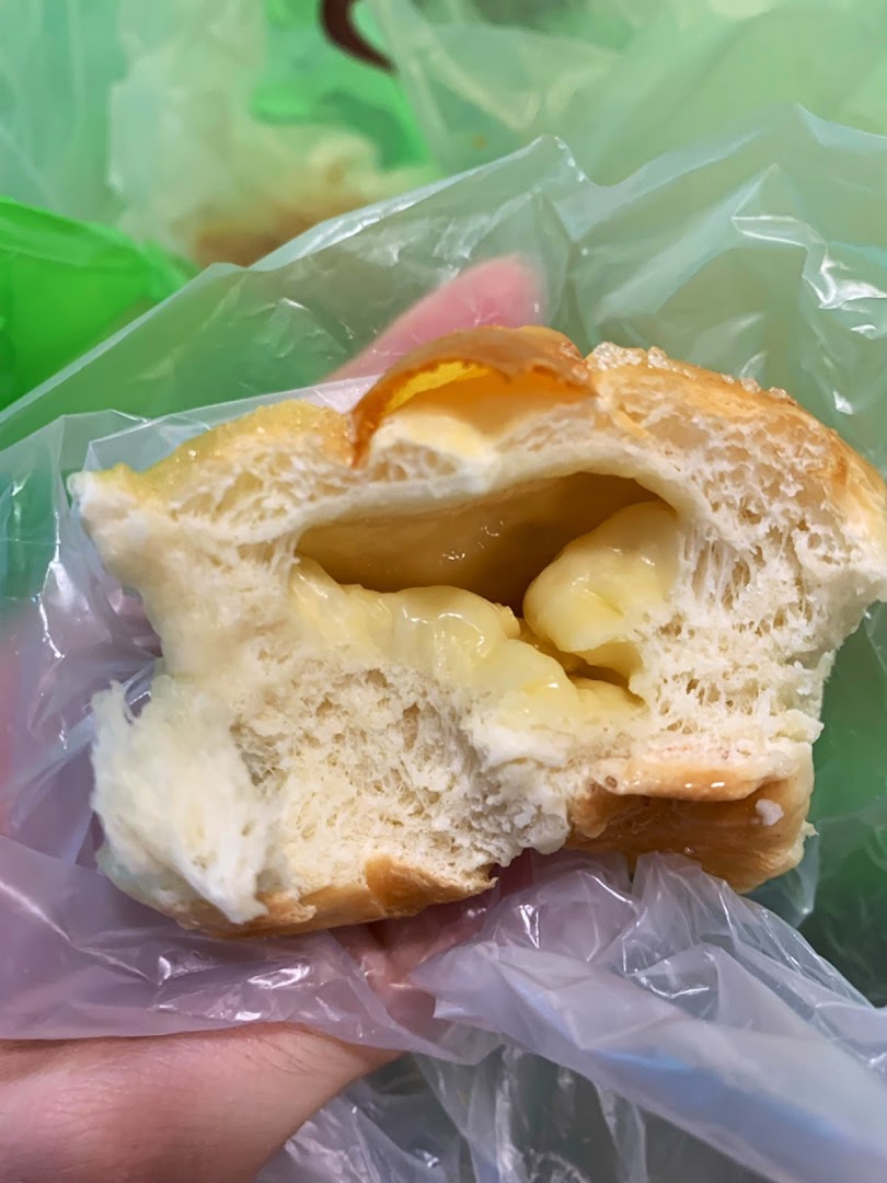 A cross-section of a bun with creamy yellow filling, held in a plastic bag.