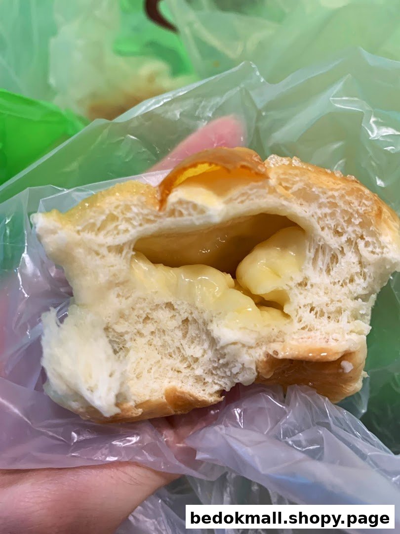 A cross-section of a bun with creamy yellow filling, held in a plastic bag.