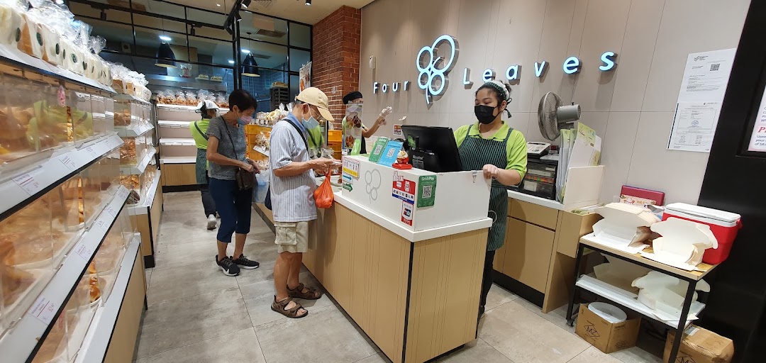 Customers and staff at the counter inside a bakery with display cases.