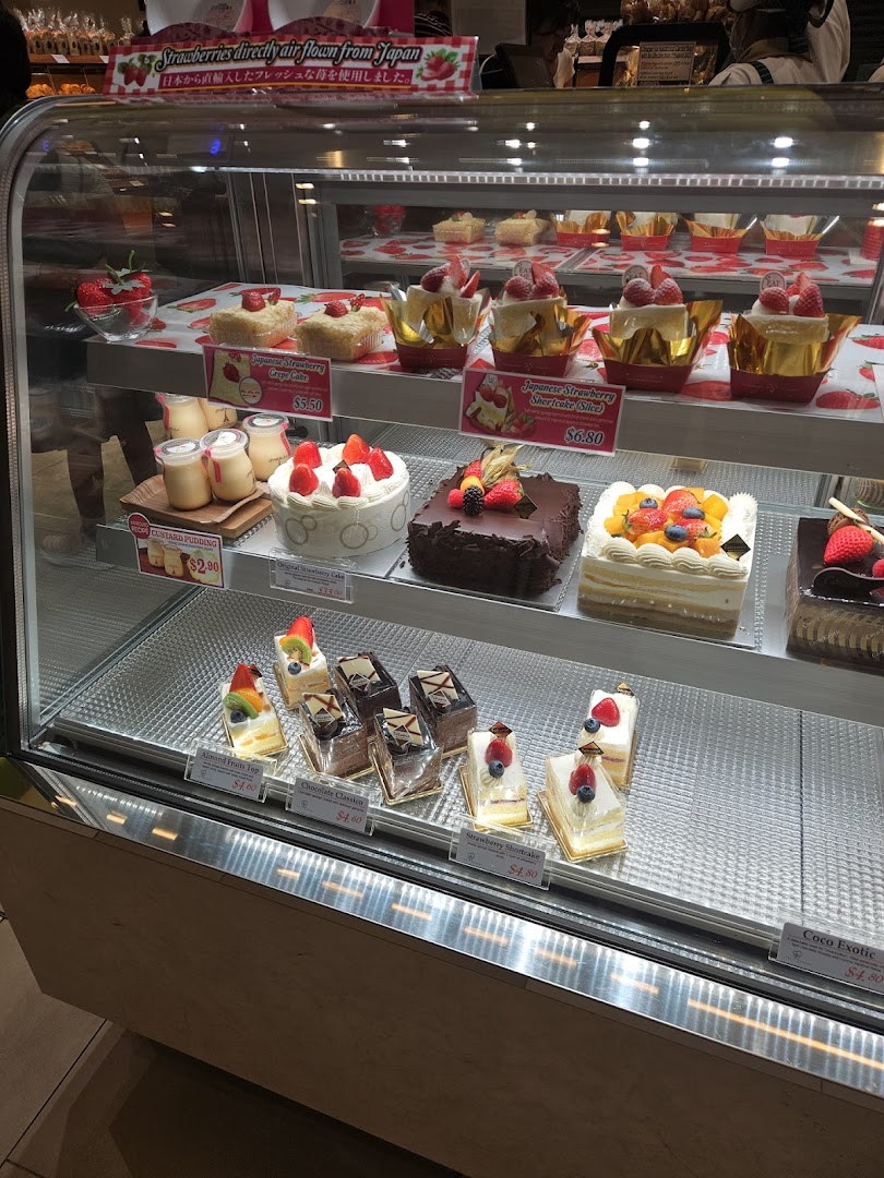 Glass display case showcasing a variety of delicious cakes and desserts.