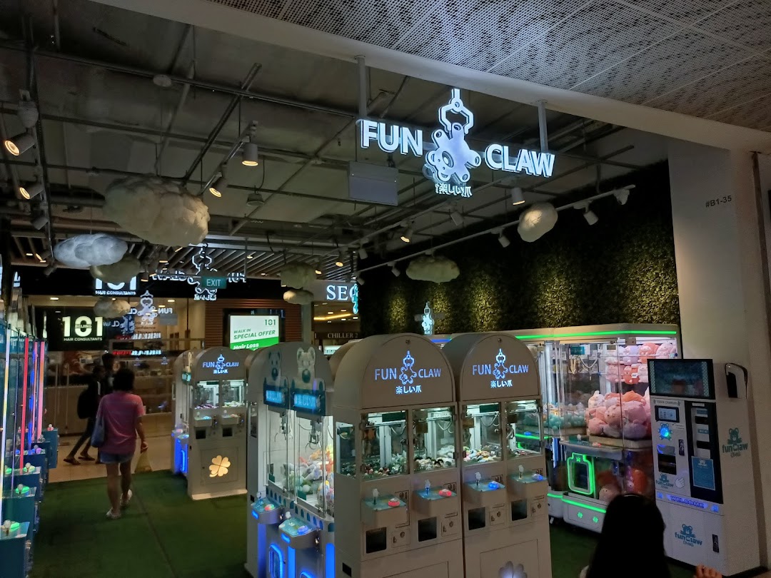 Interior view of Fun Claw arcade with multiple claw machines and people.