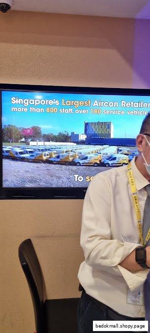 A screen displays promotional content about an aircon retailer, with a person partially visible.