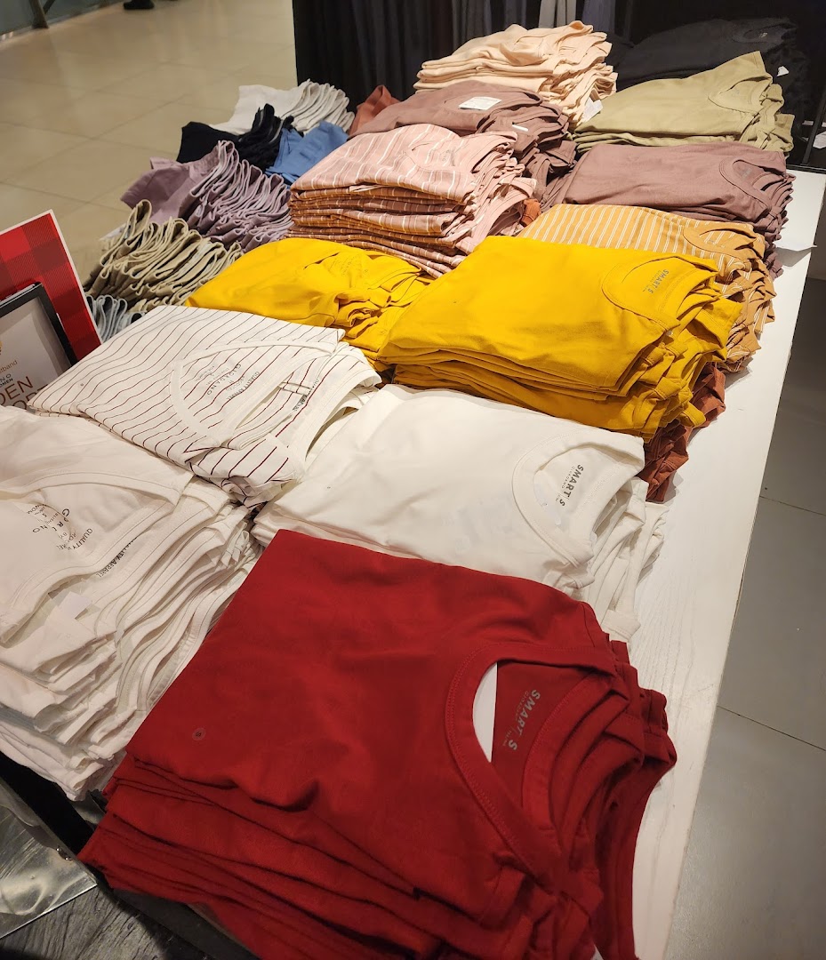 Stacks of folded apparel in various colors displayed on a table inside the shop.