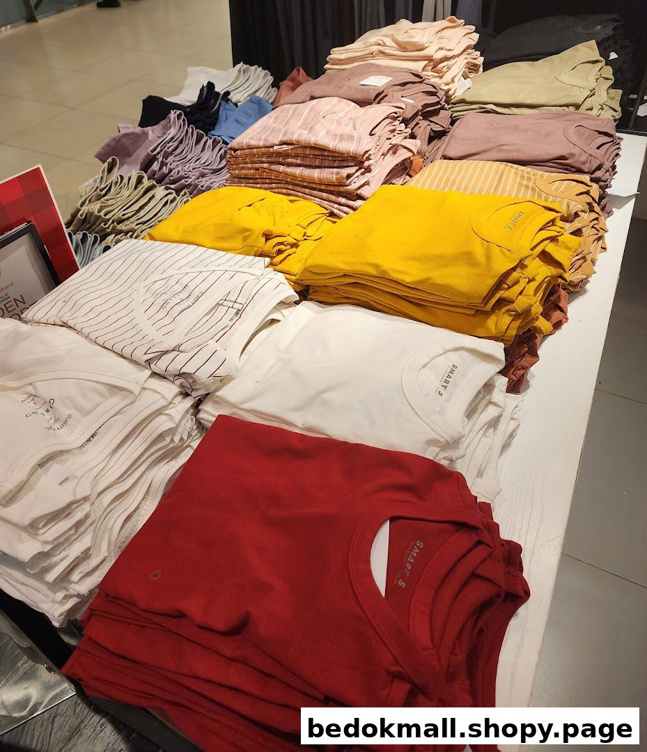 Stacks of folded apparel in various colors displayed on a table inside the shop.