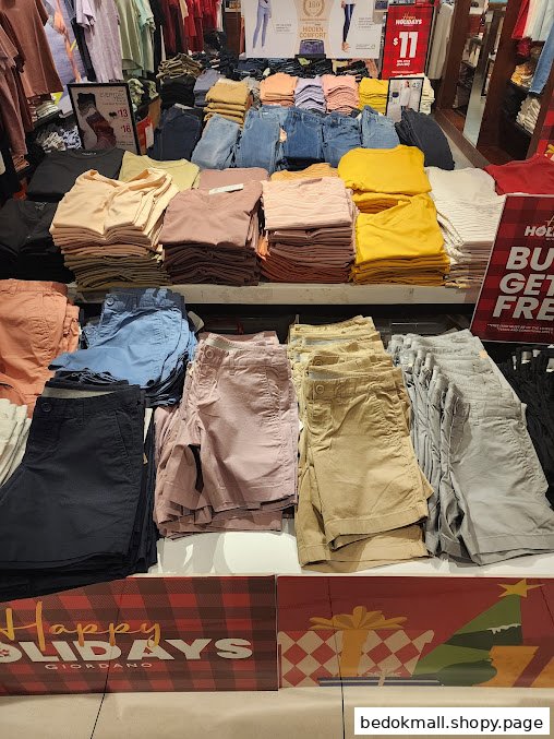 Interior view of a clothing store with folded apparel on display shelves.