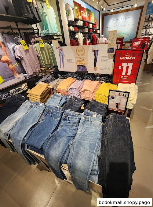 Interior view of a Giordano clothing store with jeans and folded shirts on display.