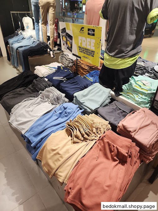 Interior view of a clothing store with folded apparel and mannequins.