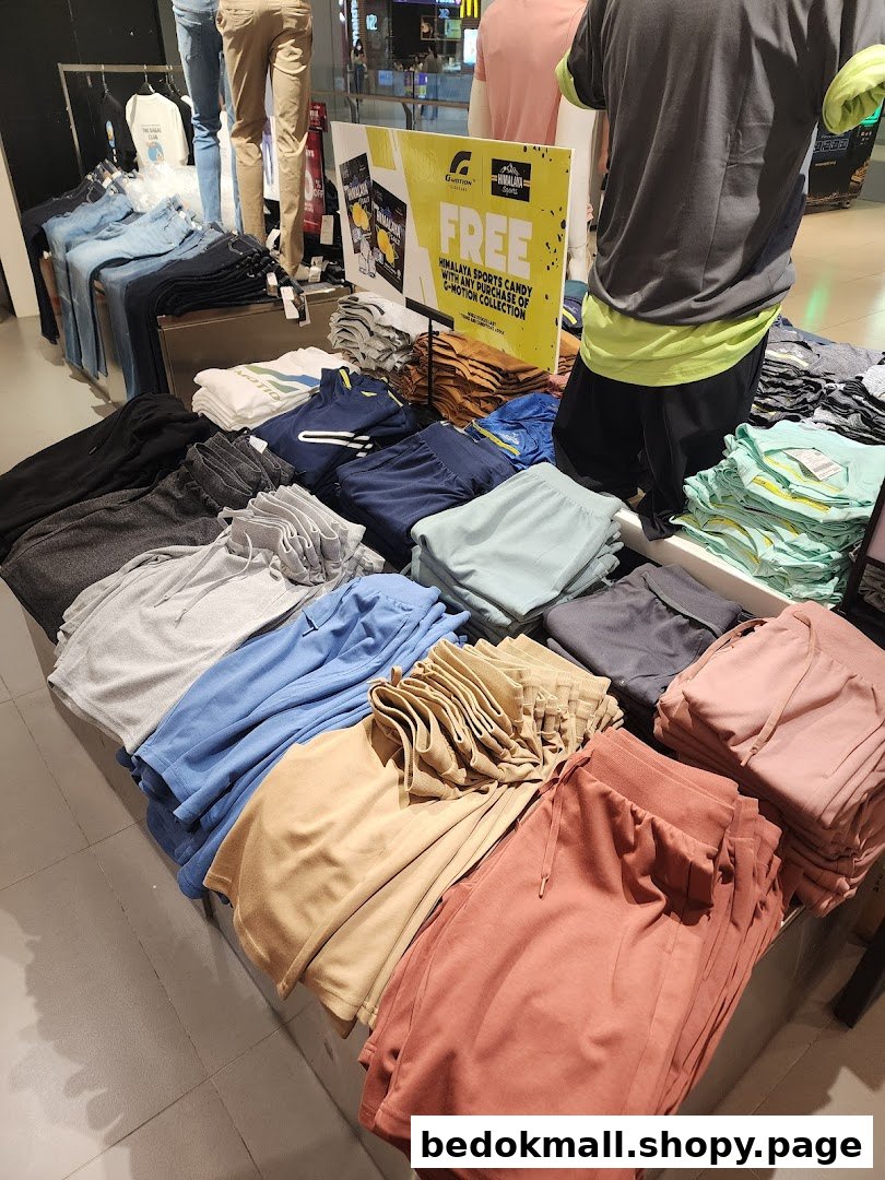 Interior view of a clothing store with folded apparel and mannequins.