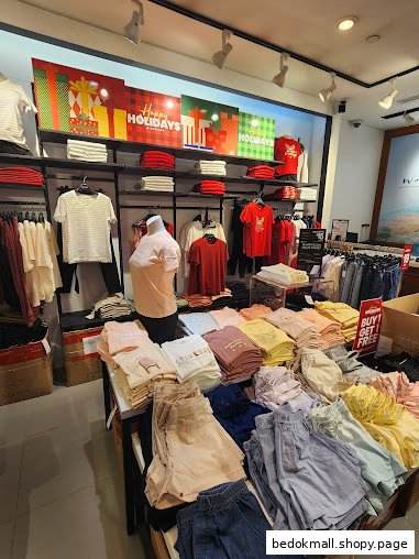 Interior of a clothing store with clothes on display and holiday decorations.