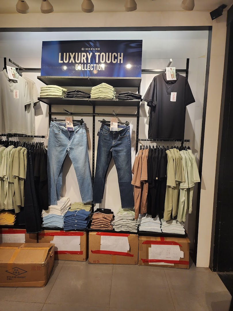 Clothing display on racks and shelves with boxes on the floor inside a shop.