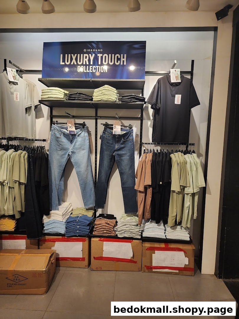 Clothing display on racks and shelves with boxes on the floor inside a shop.