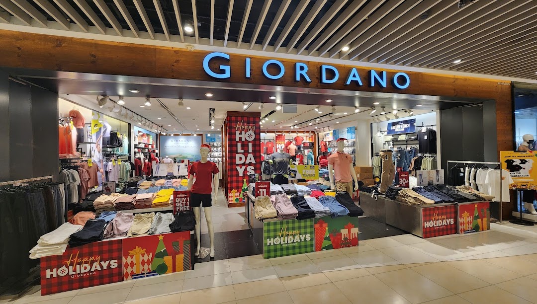 The storefront of Giordano, a clothing shop, with holiday decorations and mannequins.