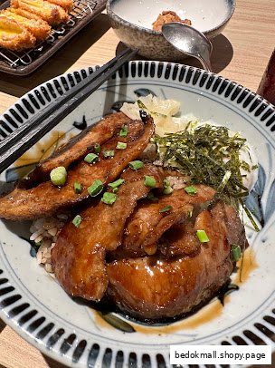 A close-up of a delicious-looking rice bowl with meat and toppings.