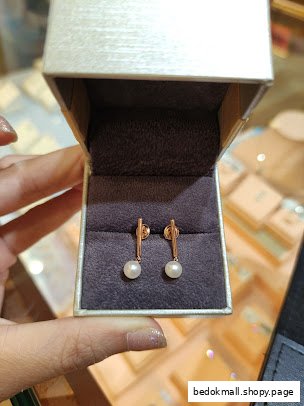 A pair of pearl earrings displayed in an open jewelry box.
