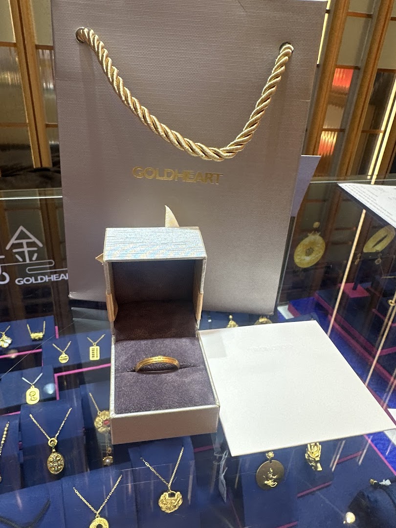 Gold ring in an open box with a Goldheart bag and jewelry display.