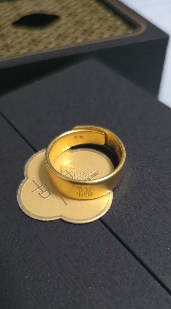 A gold ring with Chinese characters rests on a gold display base.
